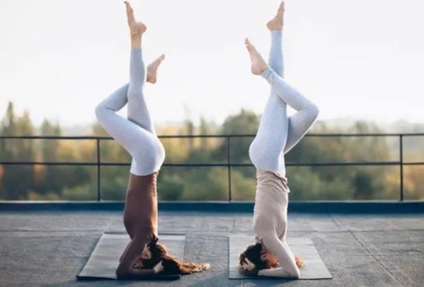 two young women doing double yoga asana