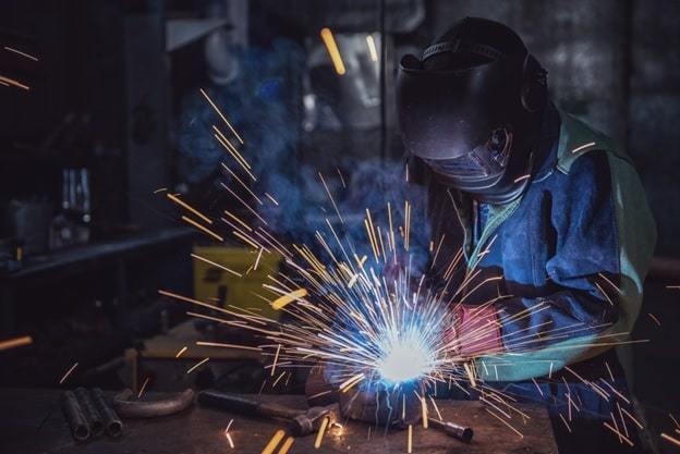 man welding creating sparks, wearing a safety helmet