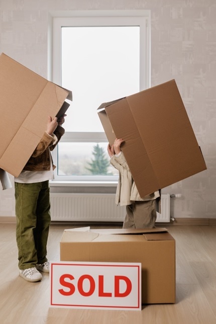 people holding brown cardboard box in sold house