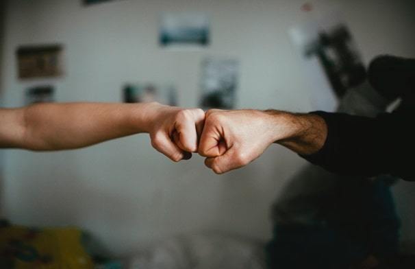 A picture of two people fist-bumping, representing the company culture in their workplace.