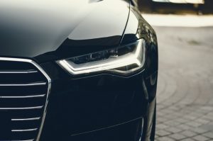 front side view of left led headlight and chrome radiator grille of the modern black car