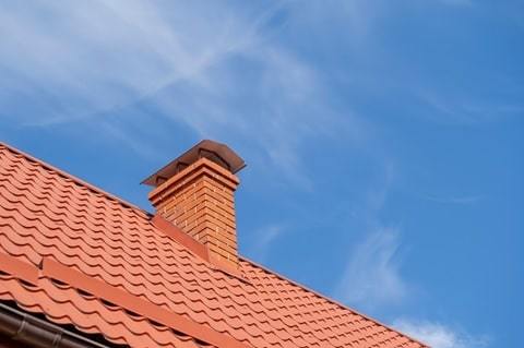 red roof house and chimney against the blue sky