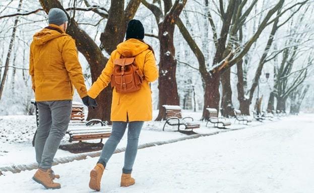 a couple holding hands while walking on a snowy road