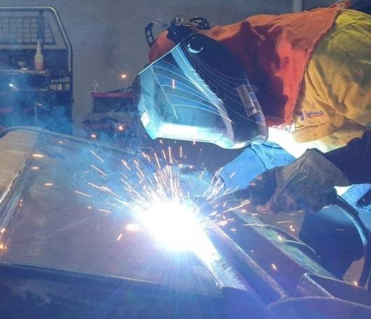 man doing welding with welding helmet