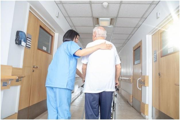 female nurse moving patient in the wheelchair through the hospital corridor