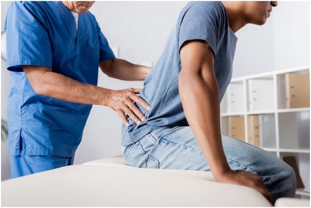 mature chiropractor working with african american man