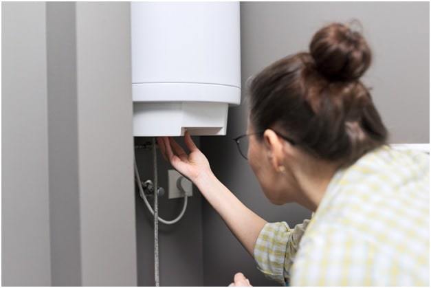 woman regulates the temperature on an electric water heater