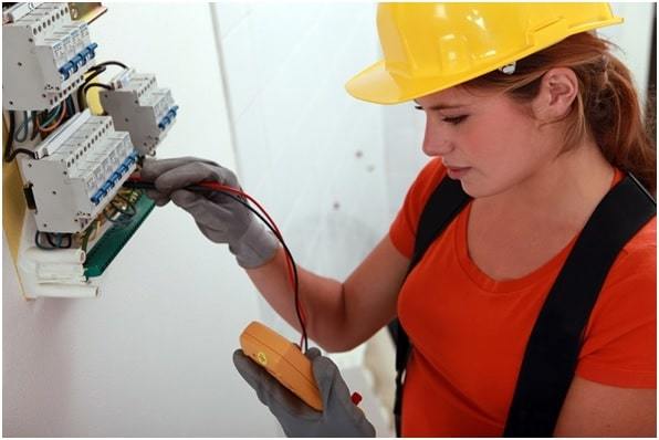 woman electrician checking electricity with multimeter