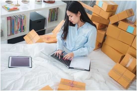 woman using laptop surrounded by packaging boxes