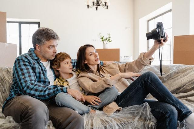 Parents and their young son sitting on a couch that's covered in plastic and taking a picture.