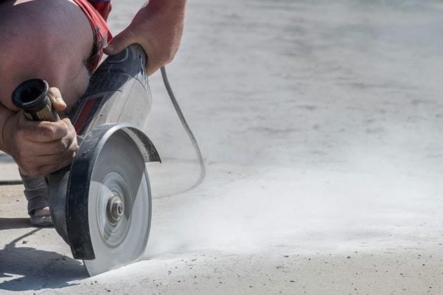 man cutting concrete floor with grinder