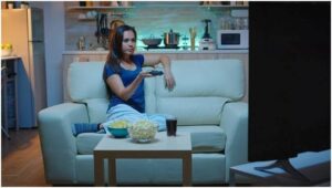 young woman eating snacks watching tv