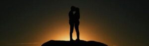 silhouette of a couple kissing at sunset on a hilltop