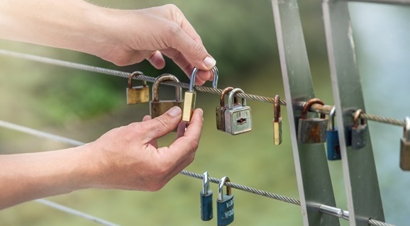 a closeup shot of hands hanging locks on a rope - concept of love