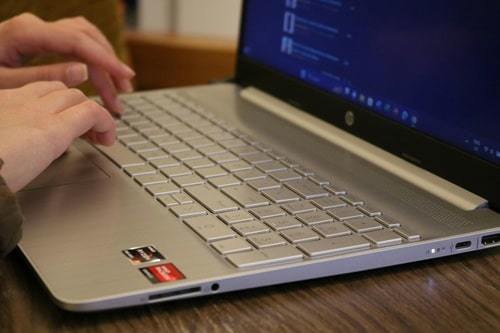 person typing on keyboard of silver laptop