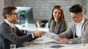 young smiling couple signing a contract while having meeting with manager
