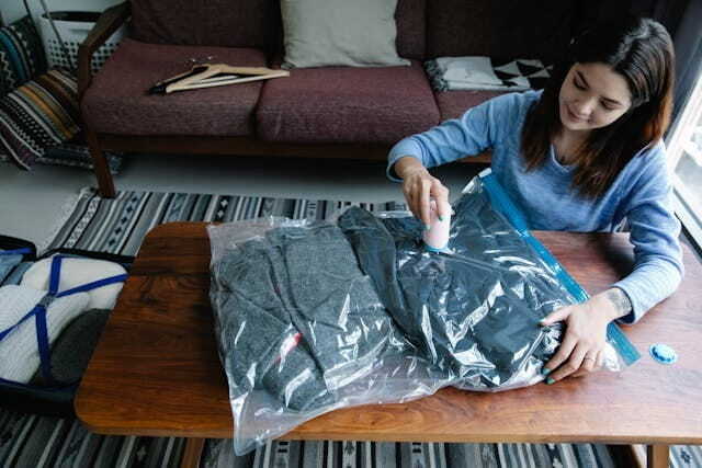 a woman vacuum packing clothes on a table
