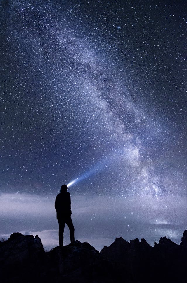 silhouette of man standing on mountain during night