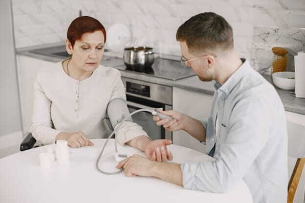 man monitoring elderly woman's blood pressure