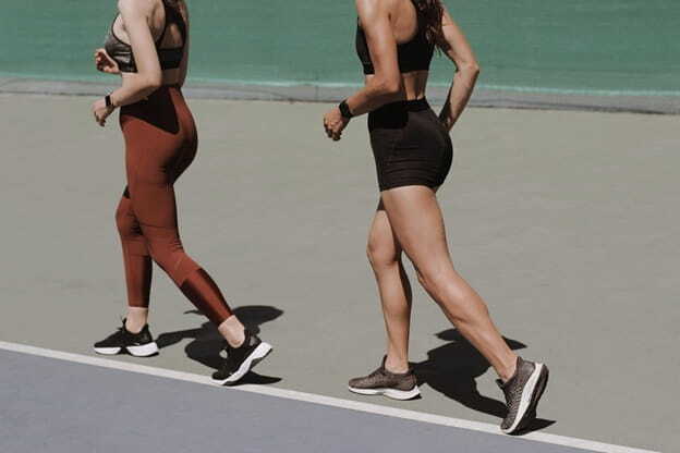 two women walking on an outdoor track in sportswear, emphasizing healthy lifestyle and fitness