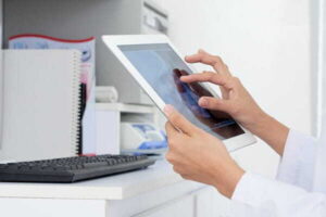 Why Burned-Out Clinicians Are Turning to AI Scribes for Faster, Audit-Ready Documentation hands unrecognizable female doctor looking human skull x ray tablet