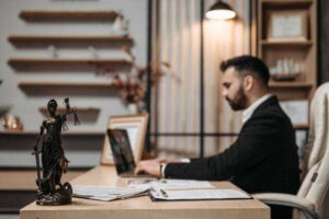 7 Ways to Reduce Stress During the Estate Resolution Process lawyer working diligently on a laptop in a modern office, lady Justice statute present