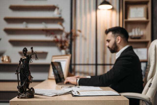 lawyer working diligently on a laptop in a modern office, lady Justice statute present