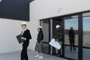 6 Best Practices for Managing Residential Investment Properties real estate agents wearing hard hats evaluate plans outside a modern building