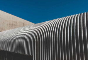 4 Investment Priorities for Long Term Property Preservation a sleek and modern corrugated metal facade with repeating stripes against a clear blue sky