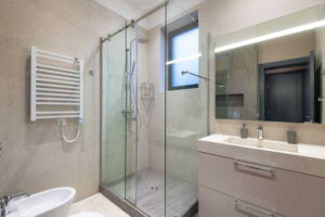 4 Reasons Homeowners Invest in Glass Surface Protection contemporary bathroom interior featuring glass shower, sink, and mirror in natural tones