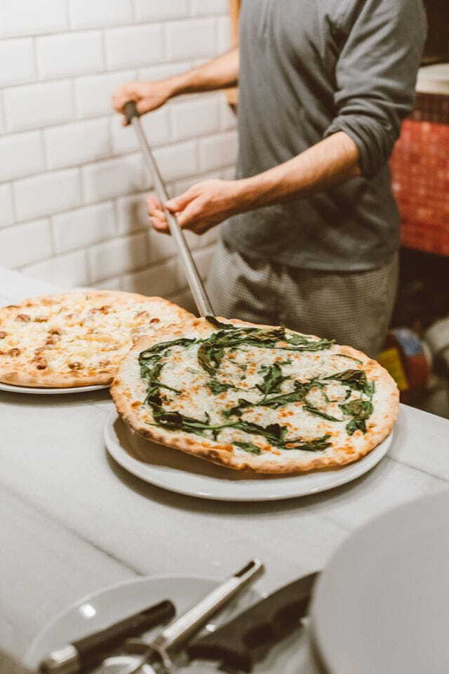 professional pizzaiolo prepares traditional pizzas in a cozy Italian restaurant