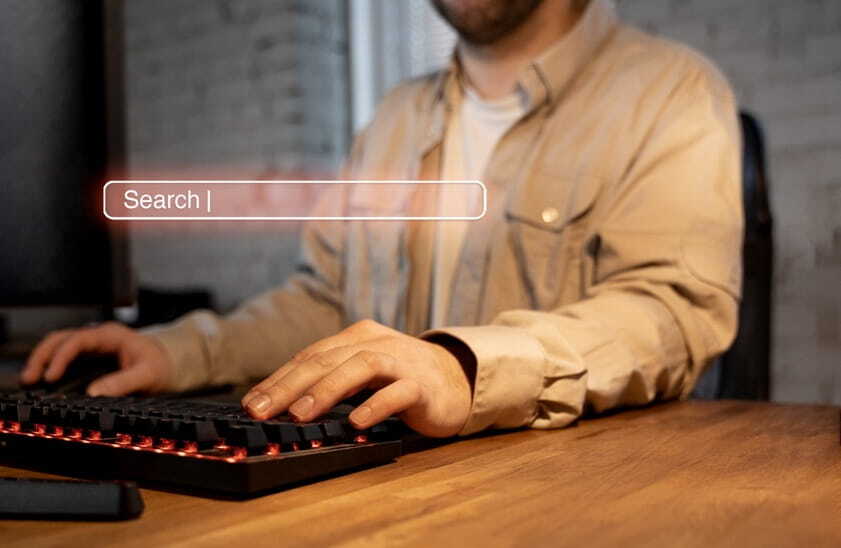 man typing on a mechanical keyboard with a search bar overlay.