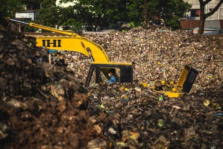 yellow and black excavator on dump site